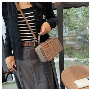 Nahaufnahme einer braunen Vintage-Quadrat-Tasche mit Ziernähten und Metallnieten-Detail