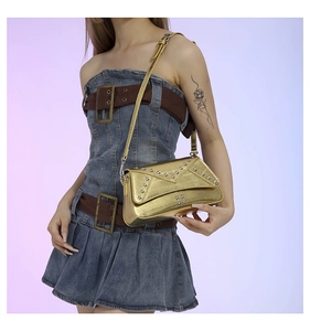 Close-up of metallic gold handbag with star studs worn by a model in denim dress