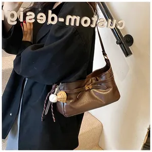 Detail of dark brown faux leather shoulder bag with gold clasp and baseball charm