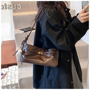 Detail of dark brown PU leather shoulder bag with metallic clasp and baseball charm