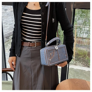 Detail der blauen Denim-Umhängetasche mit Metallnieten und braunem Lederriemen