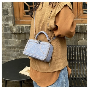 Damen Umhängetasche in hellblauem Denim mit Nieten und Doppelreißverschluss im Freien
