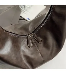 Detail of vintage brown leather hobo bag with dual metal zippers and natural texture