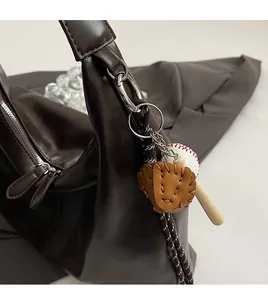 Close-up of baseball glove, ball, and bat keychain accessory on a brown leather tote bag