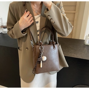 Close-up of brown PU leather bucket bag featuring a unique baseball-themed keychain charm