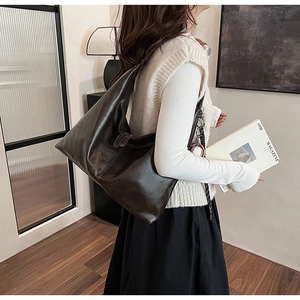 Detailed close-up of a vintage dark brown tote bag with dual zippers and ball charm detail