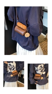 Détail du sac cylindrique marron avec décoration baguette en peluche et pendentif biscuit