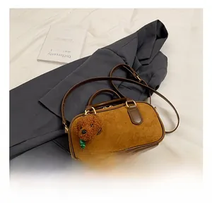 Vue détaillée du sac Boston marron rétro avec texture suédée et breloque chien