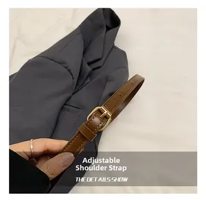 Détail de la bandoulière réglable en cuir marron avec surpiqûres blanches et boucle dorée