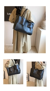 Detail of a large black woven tote bag with wide leather straps and spacious interior