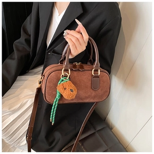 Détail du sac Boston marron mat avec pendentif ours en peluche et finitions dorées