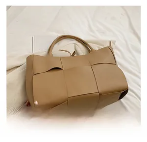 Detailed close-up of large khaki brown woven tote bag featuring wide leather straps