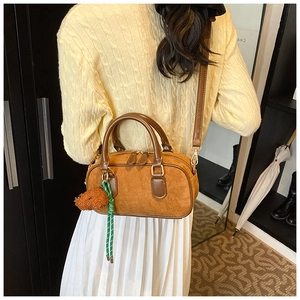 Détail d'un sac Boston en daim marron avec pendentif ours en peluche et corde tissée