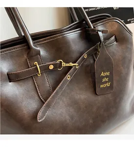 Detail of vintage brown leather tote bag showing gold hardware and textured finish