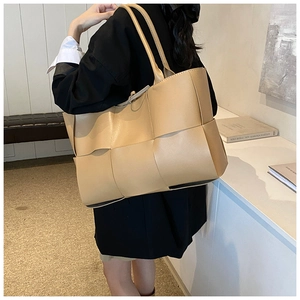 Detailed view of the large woven tote bag texture and ergonomic double handles in beige