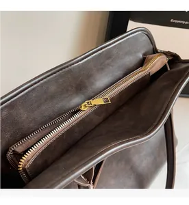 Macro shot of smooth gold metal zipper and stitching on a dark brown vintage tote bag