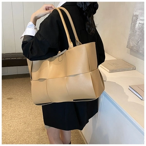 Detailed view of large khaki woven leather tote bag texture with slim shoulder straps
