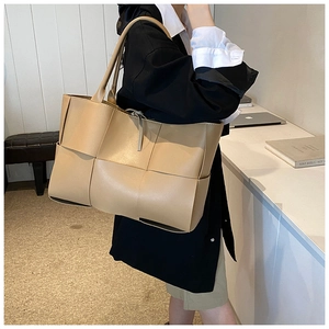 Detail of the large khaki woven leather tote bag texture and long shoulder strap