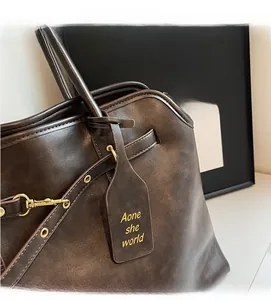 Detail of dark brown leather tote bag with branded tag and golden metal hardware accent