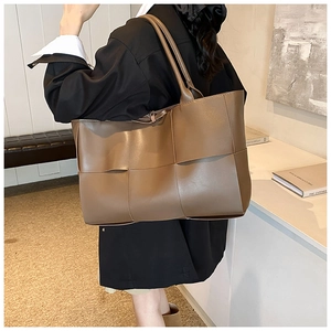 Brown woven leather tote bag with large capacity shown on model's shoulder for daily commute