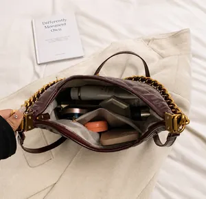 Internal capacity of the quilted burgundy saddle bag with cosmetics and gold chain strap