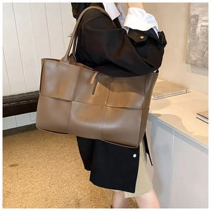 Detailed view of the dark brown woven leather tote bag texture and handle craft