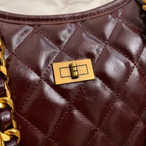 Close-up of wine red quilted saddle bag with vintage gold rectangular turn-lock buckle
