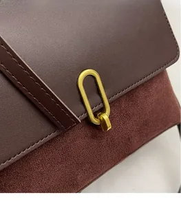 Detailed macro shot of the golden oval metal buckle on a dark brown leather handbag