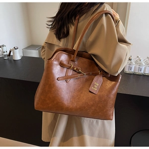 Detail of vintage brown tote bag showing textured leather and metallic buckle accents