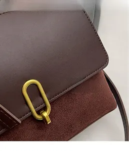 Detail of dark brown leather and suede stitching with a gold oval metal buckle