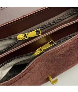 Detail of dual zipper compartments with gold metal hardware on brown suede handbag