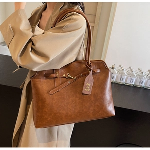 Detail of vintage brown leather tote bag with elegant metallic buckle and branded tag