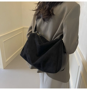 Detailed back view of a black suede hobo bag with gold zipper and wide shoulder strap