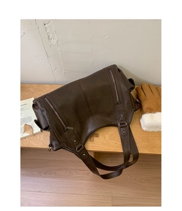 Détail du grand sac cabas vintage marron avec fermetures éclair et bandoulière sur bois