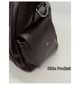 Détail du sac cabas en cuir marron foncé avec poche latérale à rabat et boucle en métal