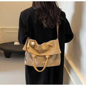 Detail of khaki suede tote bag with creative baseball charm and wide shoulder strap