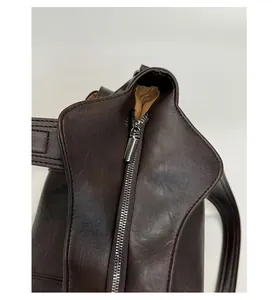 Détail de la fermeture éclair argentée et du cuir marron foncé du sac fourre-tout