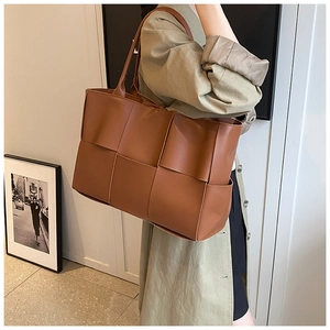Detail of a brown woven tote bag featuring an intricate leather Intrecciato pattern