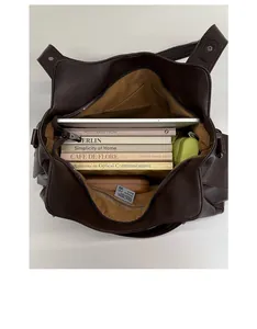 Vue de dessus d'un grand sac cabas marron foncé contenant des livres et des accessoires