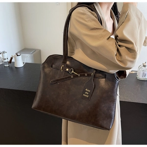 Detail of vintage brown tote bag featuring matte texture and antique gold hardware