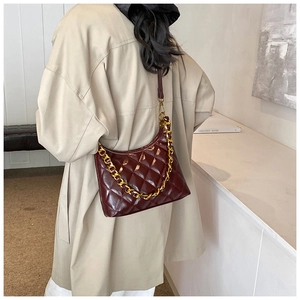 Detail of dark burgundy quilted hobo bag with gold chain strap worn by a model