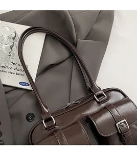 Detail of dark brown glossy leather shoulder bag with functional silver buckle pockets