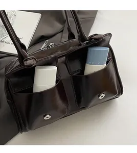 Detail of dark brown leather shoulder bag featuring two front magnetic flap pockets for storage