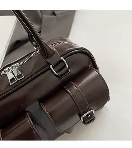 Close-up of dark brown glossy leather handbag with silver metallic zippers and hardware