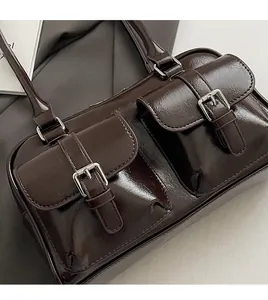 Close-up of a glossy dark brown leather bag with silver metal buckles and pockets