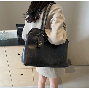Detail of vintage matte black tote bag with shoulder straps and leather brand tag