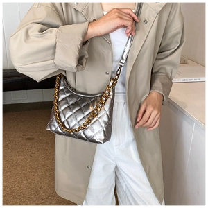 Detail of silver quilted saddle bag with gold chain strap and sleek metallic finish