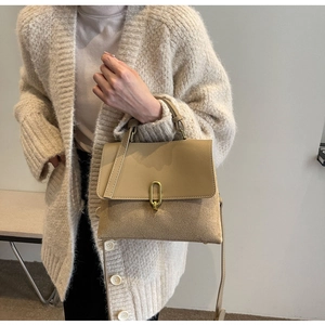 Close-up of minimalist beige handbag showing premium leather texture and gold oval lock