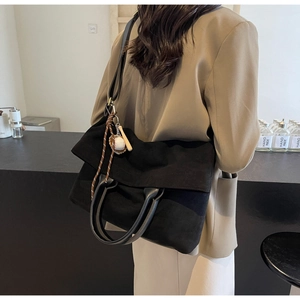Dettaglio borsa shopper nera con ciondolo da baseball e manico cilindrico sulla modella
