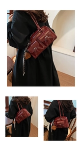 Detail of dark red vintage shoulder bag with utility pockets and bear charm